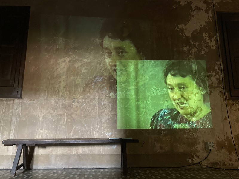 Projektion einer Frau an der Wand eines kahlen Raumes