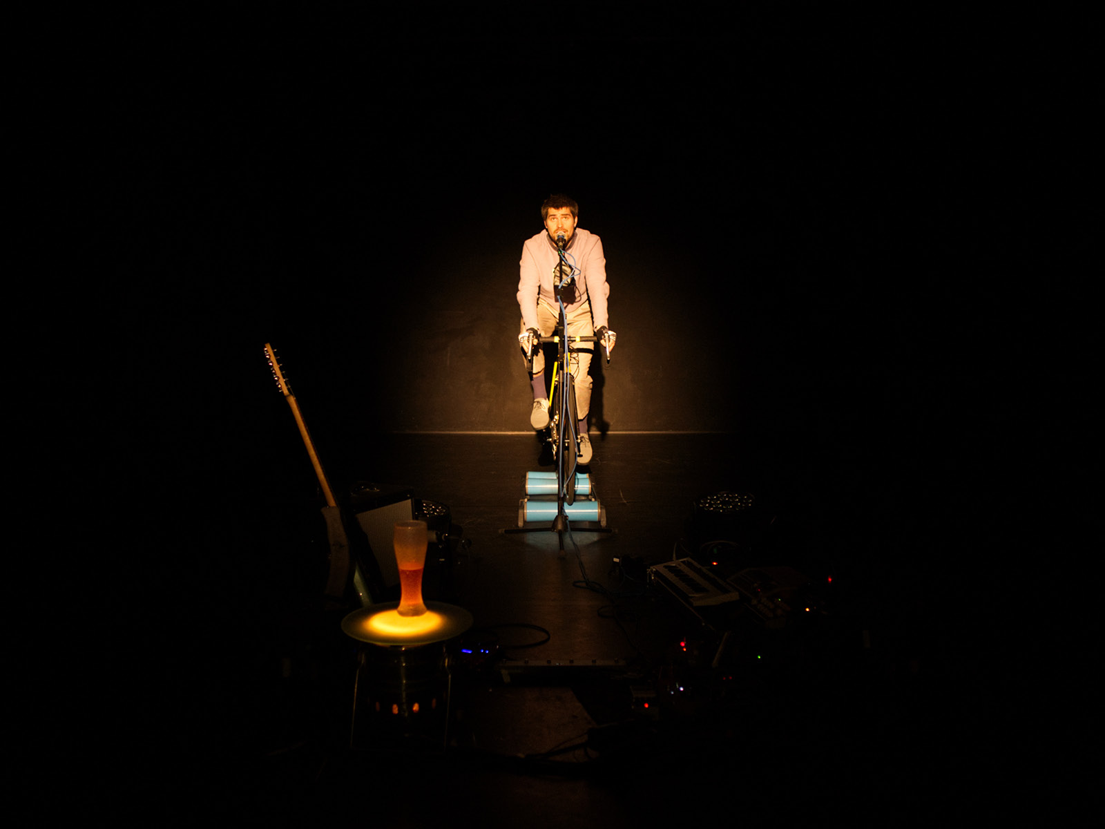 Spieler auf fast leerer Bühne auf einem Fahrrad.