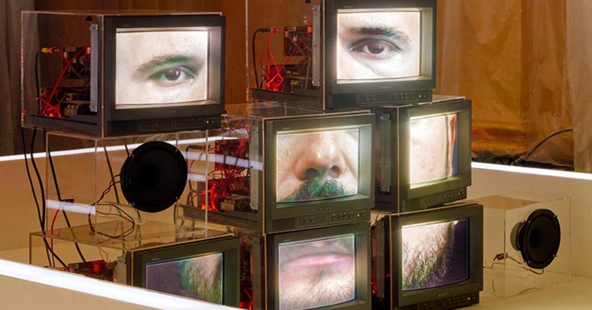 Eine Installation aus Monitoren zeigt ein männliches Gesicht. Wobei ein Monitor einen Gesichtsteil wie beispielsweise ein Auge zeigt. In Summe ergeben sie ein Gesicht.