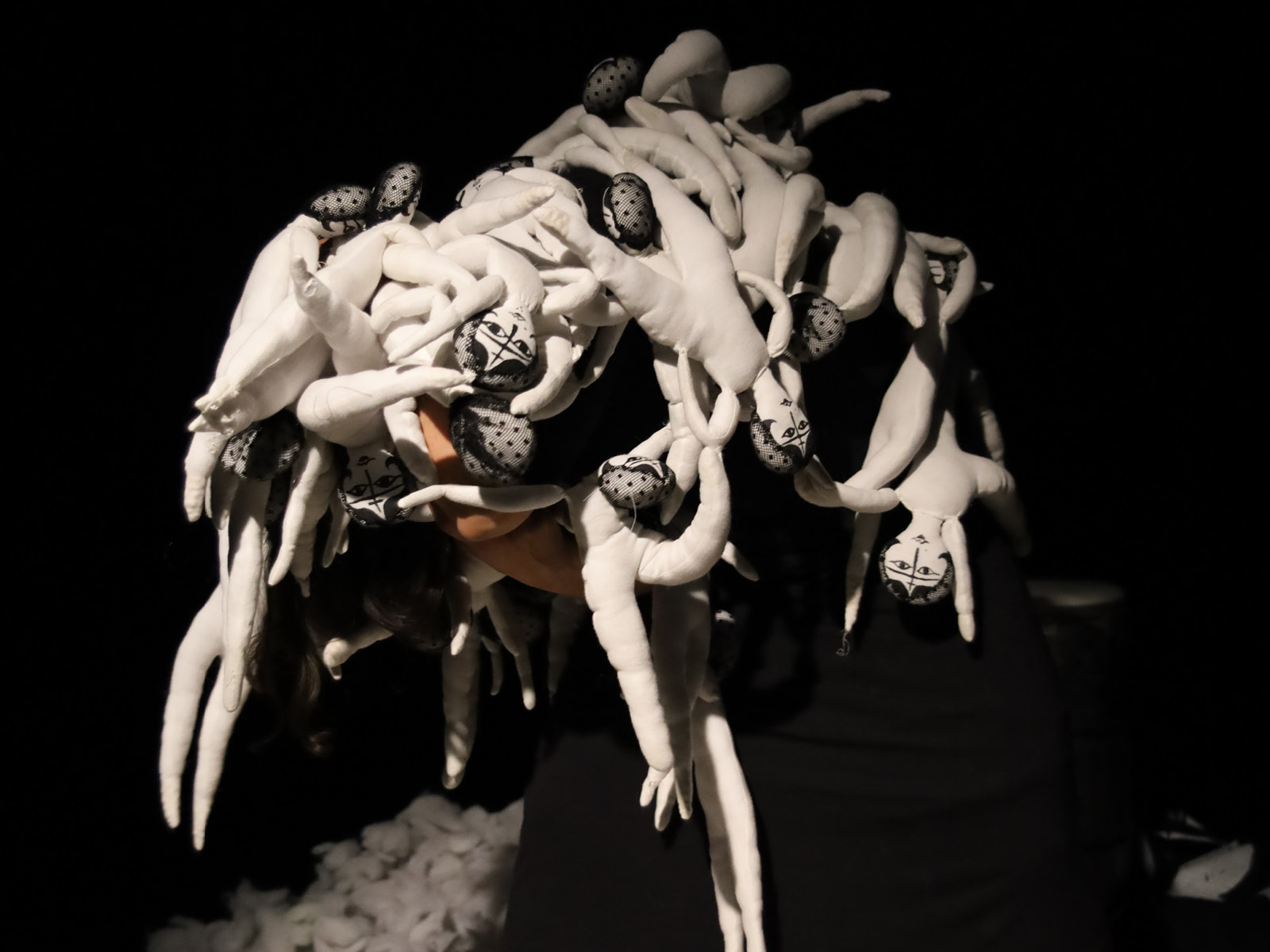 A person holds a bunch of small white dolls in his hands.